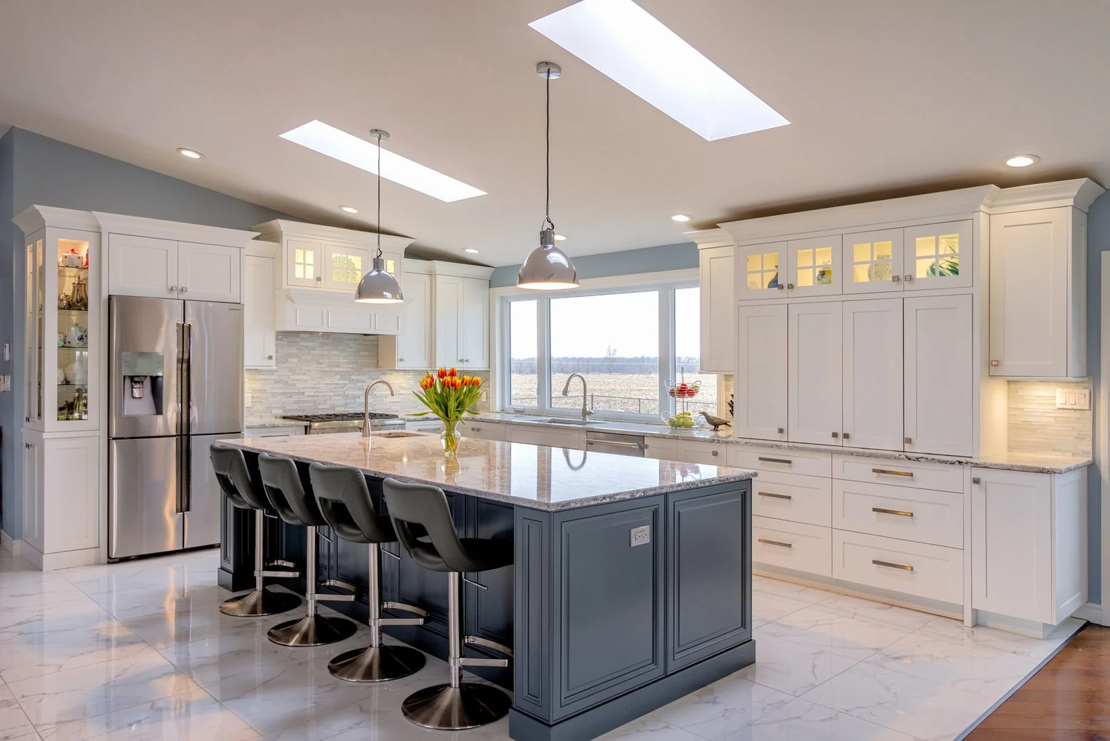 White kitchen cabinetry and a contrasting dark island beneath skylights