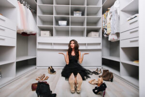 walk-in closet design ideas -beautiful young woman sitting floor big nice dressing room around shoes doesnt know what wear is appointed tired making choice-wearing-black-dress-scaled.jpg